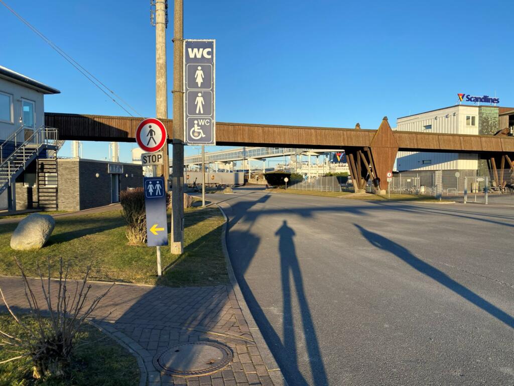 Fußgängerbrücke zum Terminal und WC-Schild am Fährhafen Puttgarden